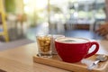 Close up Red cup hot cappuccino coffee with biscuits on wooden tray with soft light on glass table  moment of happiness with Royalty Free Stock Photo