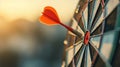 Close up red dart arrow hitting target center dartboard on sunset background. Business targeting and focus concept. Royalty Free Stock Photo