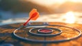 Close up red dart arrow hitting target center dartboard on sunset background. Business targeting and focus concept. Royalty Free Stock Photo