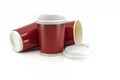 Close up red disposable paper cups or takeaway cup for hot drinks with lid on white background, one stand as usual and the others