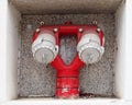Close up of a red double emergency outdoor fire hydrant inset into the wall of a building Royalty Free Stock Photo