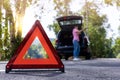 Close up red emergency stop sign standing on road. Worried and angry woman walking near his broken car talking on phone with Royalty Free Stock Photo