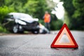 A close up of a red emergency triangle on the road in front of a car after an accident. Royalty Free Stock Photo