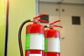 Close up the red fire extinguisher tank with fire exit door in the building Royalty Free Stock Photo