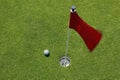 Red flag on green with golf ball. Royalty Free Stock Photo