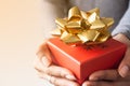 Close up red gift box with gold colour ribbon on woman hands Royalty Free Stock Photo