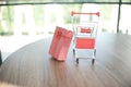 Close up red gift box and shopping cart on table for shopping and e-commerce concept Royalty Free Stock Photo