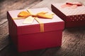 Close-up red gift box with a yellow ribbon tied with a bow on a wooden background: concept of a holiday or romantic gift Royalty Free Stock Photo