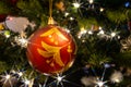 Close up of a red and golden Christmas bauble hanging in a Christmas tree