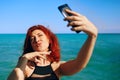 Red-haired woman takes selfie on smartphone camera. Royalty Free Stock Photo