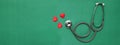 Close up red heart white stethoscope on green Doctor table.health concept.