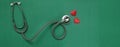 Close up red heart white stethoscope on green Doctor table.health concept.