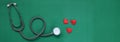 Close up red heart white stethoscope on green Doctor table.health concept.