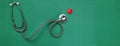 Close up red heart white stethoscope on green Doctor table.health concept.