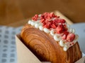 Close-up red iced strawberries and soft cream on brown cake or croissant bread. Royalty Free Stock Photo