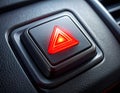 Red illuminated hazard warning triangle button on a car\'s textured dashboard light Royalty Free Stock Photo