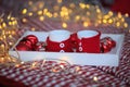 Close-up of red knitted mugs on glowing bokeh background. Cup of hot chocolate or coffe with Christmas on tray with decorations