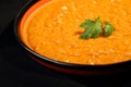 Close up of red lentil stew in an orange and black bowl with a green parsley leaf in it. Homemade, delicious, vegan and healthy Royalty Free Stock Photo