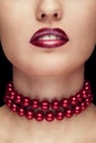 Close up red lips and pearls arround neck on black background