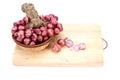 Close up red onion or shallots in wooden basket with sliced onion on wooden chopping block