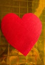 Close-up of red paper heart on gold holographic wrapping paper background, vertical photo, copy space