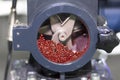 Close up red plastic granules in crusher machine with blade of cutting prepare material for injection process