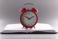 Red retro clock stand on top of open notebook or book