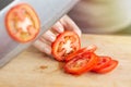 Close up of red ripe tomato cutting with a knife. Healthy food preparation concept