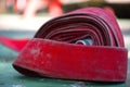 Close up of red rolled up fire extinguishing hose with coupling and nozzle, Red old Fire Hose texture on the floor, Firefighters