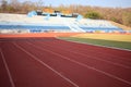 Close up, the red running track floor has white lines in the outdoor stadium for the background.