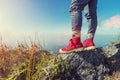 Close up of red shoes of traveller standing on mountain peak wit