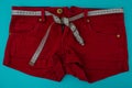 Close-up red shorts with a centimeter instead of a belt on a blue background, next to an empty area.