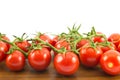 Close up of red small cherry tomatoes on a wooden surface and white background Royalty Free Stock Photo