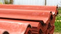 Close-up of red steel roofing panels piles lying outside and prepared for house`s roof construction. Clip. Materials and