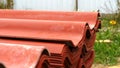 Close-up of red steel roofing panels piles lying outside and prepared for house`s roof construction. Clip. Materials and