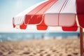 Close up of red and white striped sun parasol with blurry beach in background Royalty Free Stock Photo