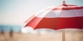Close up of red and white striped sun parasol with blurry beach and ocean in background Royalty Free Stock Photo