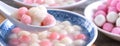 Close up of red and white tangyuan in blue bowl on wooden background for Winter solstice