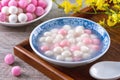 Close up of red and white tangyuan in blue bowl on wooden background for Winter solstice