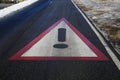 Close up of red white triangle danger warning sign on asphalt of slippery road with snow and black ice focus on center of sign Royalty Free Stock Photo