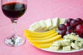 Close-up of red wine glass and tree kinds of sliced cheese and sweet red grapes on white plate. Cheeses covered with edible white Royalty Free Stock Photo