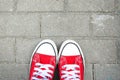 Close-up of red women`s sneakers on the background of grey asphalt tiles.