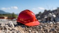 Close up of a red Working Helmet on Gravel. Blurred Construction Site Background