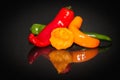 Close-up of red, yellow and green chili peppers lying on black reflectin background Royalty Free Stock Photo
