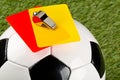 Close up of referee yellow and red cards and chrome whistle on top of soccer ball over grass background - penalty, foul or sports Royalty Free Stock Photo