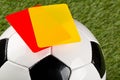 Close up of referee yellow and red cards on top of soccer ball over grass background - penalty, foul or sports concept Royalty Free Stock Photo