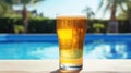 A close-up of a refreshing pint of cold beer, glistening with condensation, on the edge of a pool on a sunny day Royalty Free Stock Photo