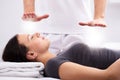 Young Woman Receiving Reiki Treatment By Therapist