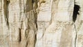 Close-up of relief white cliff slope and large grotto in the middle of slope. Shot. Majestic mountain cliff