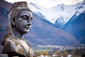 close-up of a religious statue placed against a mountain village backdrop